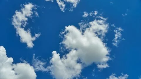 White fluffy clouds in the sky. Blue sky and cloud cover on a sunny summer da Stock Photos