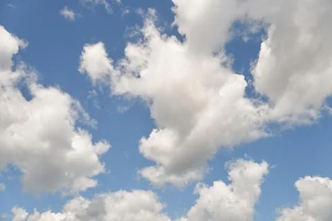 White fluffy clouds in the sky. Blue sky and cloud cover on a sunny summer da Stock Photos