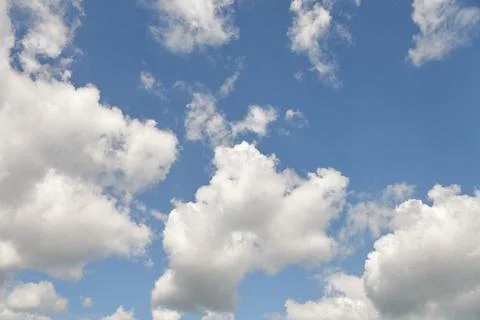 White fluffy clouds in the sky. Blue sky and cloud cover on a sunny summer da Stock Photos