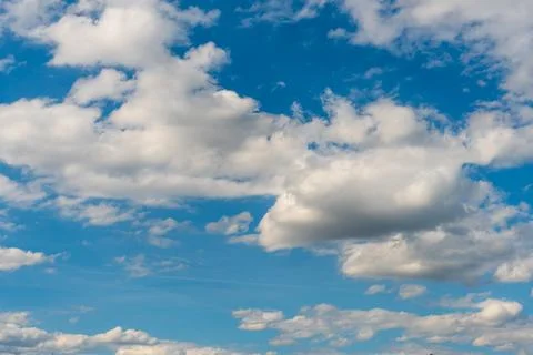 White fluffy clouds in the sky. Blue sky and cloud cover on a sunny summer da Stock Photos