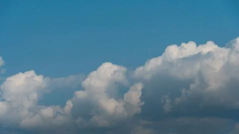 White fluffy clouds in the sky. Blue sky and cloud cover on a sunny summer da Stock Photos