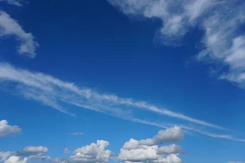 White fluffy clouds in the sky. Blue sky and cloud cover on a sunny summer da Stock Photos