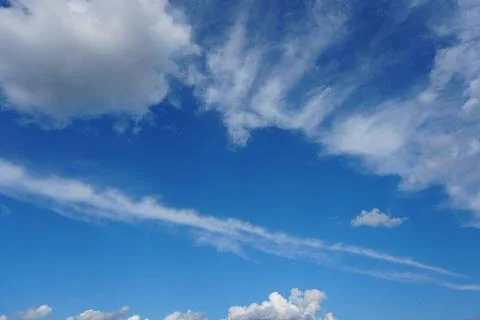 White fluffy clouds in the sky. Blue sky and cloud cover on a sunny summer da Stock Photos