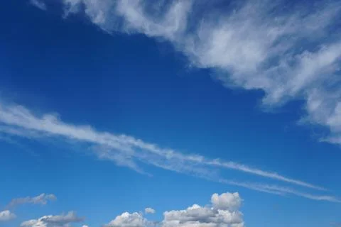 White fluffy clouds in the sky. Blue sky and cloud cover on a sunny summer da Stock Photos