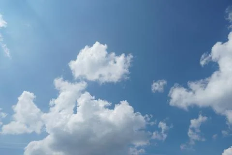 White fluffy clouds in the sky. Blue sky and cloud cover on a sunny summer da Stock Photos