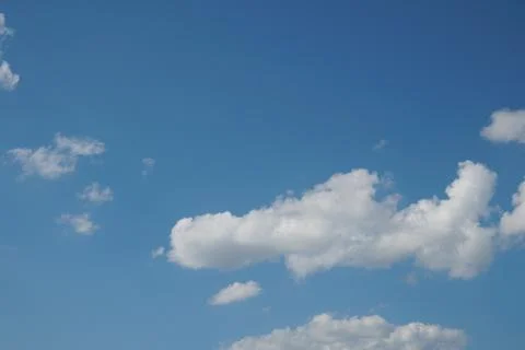 White fluffy clouds in the sky. Blue sky and cloud cover on a sunny summer da Stock Photos