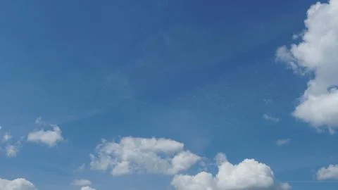 White fluffy clouds in the sky. Blue sky and cloud cover on a sunny summer da Stock Photos