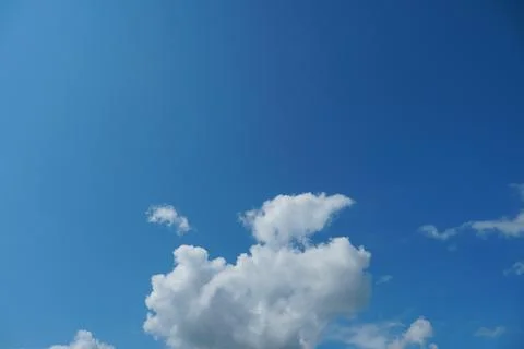 White fluffy clouds in the sky. Blue sky and cloud cover on a sunny summer da Stock Photos