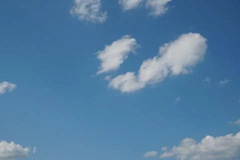 White fluffy clouds in the sky. Blue sky and cloud cover on a sunny summer da Stock Photos