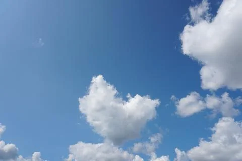 White fluffy clouds in the sky. Blue sky and cloud cover on a sunny summer da Stock Photos