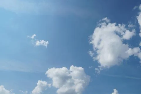 White fluffy clouds in the sky. Blue sky and cloud cover on a sunny summer da Stock Photos