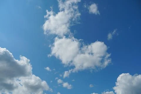 White fluffy clouds in the sky. Blue sky and cloud cover on a sunny summer da Stock Photos