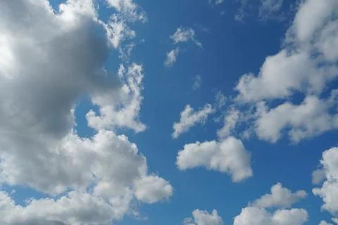 White fluffy clouds in the sky. Blue sky and cloud cover on a sunny summer da Stock Photos