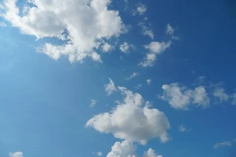 White fluffy clouds in the sky. Blue sky and cloud cover on a sunny summer da Stock Photos