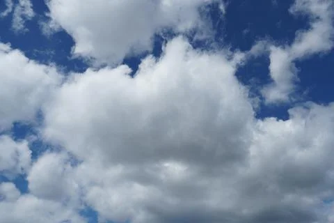 White fluffy clouds in the sky. Blue sky and cloud cover on a sunny summer da Stock Photos