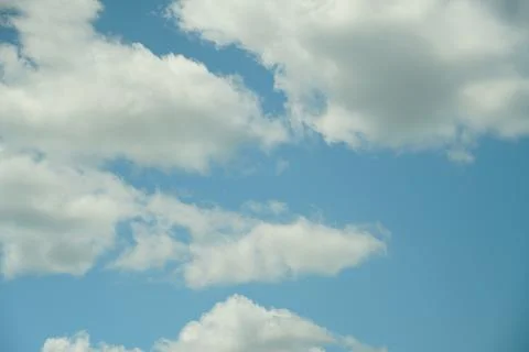 White fluffy clouds in the sky. Blue sky and cloud cover on a sunny summer da Stock Photos