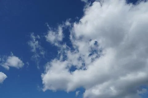 White fluffy clouds in the sky. Blue sky and cloud cover on a sunny summer da Stock Photos