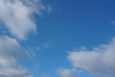 White fluffy clouds in the sky. Blue sky and cloud cover on a sunny summer da Stock Photos