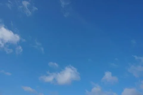 White fluffy clouds in the sky. Blue sky and cloud cover on a sunny summer da Stock Photos