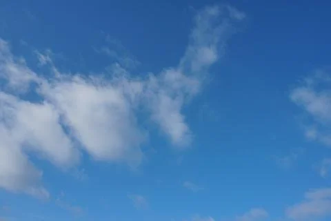 White fluffy clouds in the sky. Blue sky and cloud cover on a sunny summer da Stock Photos