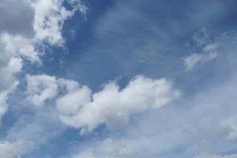 White fluffy clouds in the sky. Blue sky and cloud cover on a sunny summer da Stock Photos