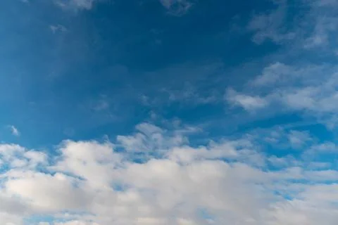 White fluffy clouds in the sky. Blue sky and cloud cover on a sunny summer da Stock Photos
