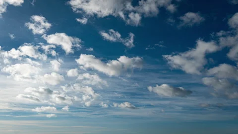 White Fluffy Clouds Slowly Float Through the Blue Daytime Sky Timelapse Video stock 260470567