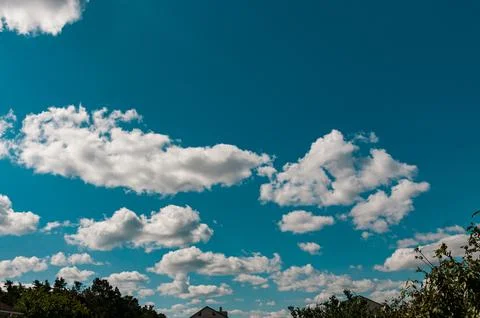 White fluffy clouds in a vibrant blue summer sky Stock Photos