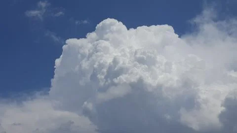 White, fluffy cumulus clouds alone in a blue sky. Stock Photos