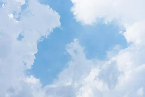 White fluffy cumulus clouds floating across a bright blue summer Stock Photos