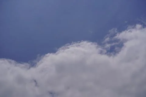 White fluffy cumulus clouds floating in a clear blue sky during a bright sunn Stock-Fotos