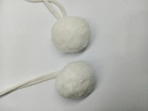 White fluffy pom poms with strings on white background Stock Photos