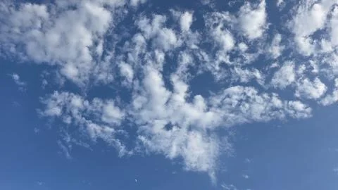 White fluffy scattered clouds spreading across bright blue sky on sunny day.. Stock Photos