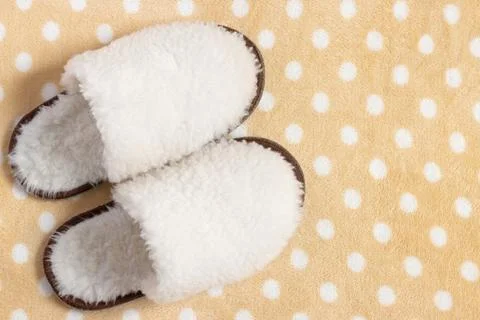 White fluffy slippers on a carpet with a dot print Stock Photos