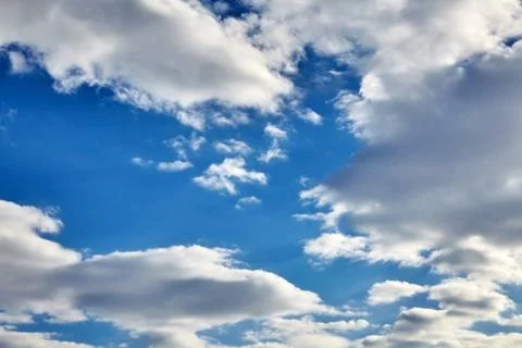White fluffy soaring clouds on a blue sky background Stock Photos