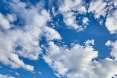White fluffy soaring clouds on a blue sky background Stock Photos
