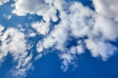 White fluffy soaring clouds on a blue sky background Stock Photos