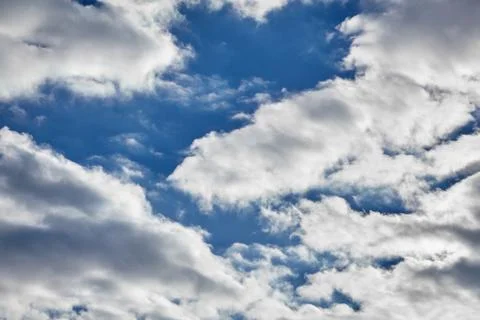 White fluffy soaring clouds on a blue sky background Stock Photos