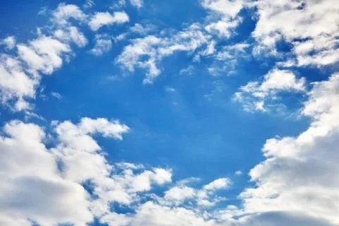 White fluffy soaring clouds on a blue sky background Stock Photos