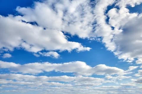White fluffy soaring clouds on a blue sky background Stock Photos