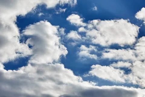 White fluffy soaring clouds on a blue sky background Stock Photos