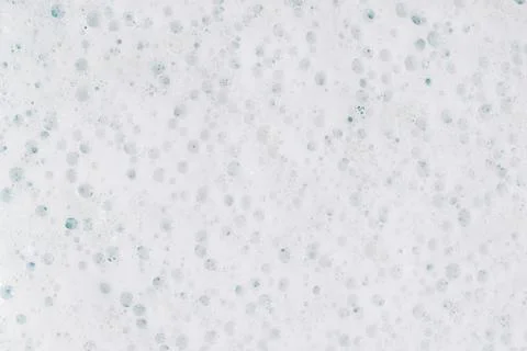 White Foam on a blue background. Soapy liquid texture with bubbles. Stock Photos