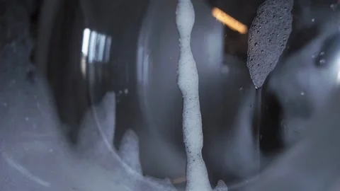 White foam flows down the glass door of a washing machine Stock Footage 130916844
