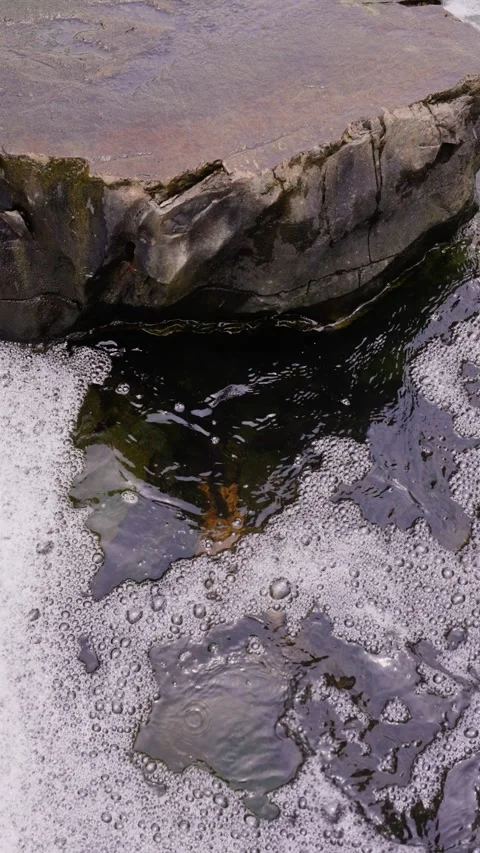 White foam flows in the rock pool below the waterfall Stock Footage 340485573