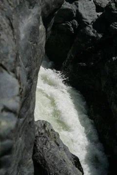 White foam on a rushing stream through black rocks Stock Photos