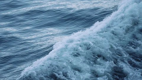 White foam of a ship bow wave over rippled blue water close up Stock-Footage 347827031