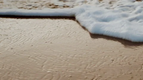 White foam surf at sunset on a beach with golden sand on a warm sunny day Stock Footage 147559314