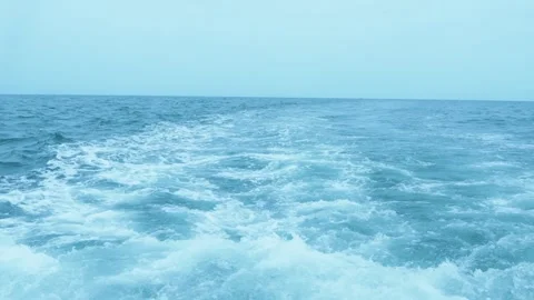 White foamy wake left by a boat on the turquoise blue ocean surface under a.. Vidéo 346221716