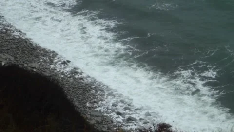 White foamy waves lapping against the rocky shore. The sea in a storm Stock Footage 304876849