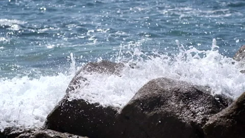 White foamy waves splashing over rocks on the beach in slow motion, close up. Stock Footage 151874850